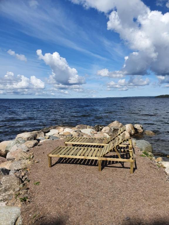 TivedHamgården Nature Resort Tiveden的木凳坐在靠近水面的岩石上
