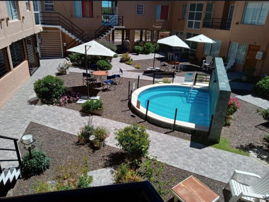 拉斯格路塔斯Complejo Ali Lafken的庭院设有游泳池、桌子和遮阳伞