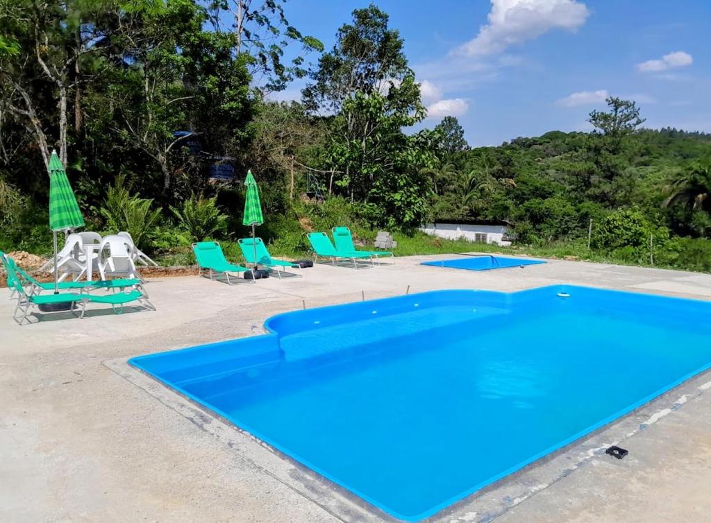 茹基蒂巴Casas de Campo Beija-Flor & Bem-Te-Vi, Mata Atlântica, Juquitiba, SP的一个带椅子和遮阳伞的蓝色游泳池