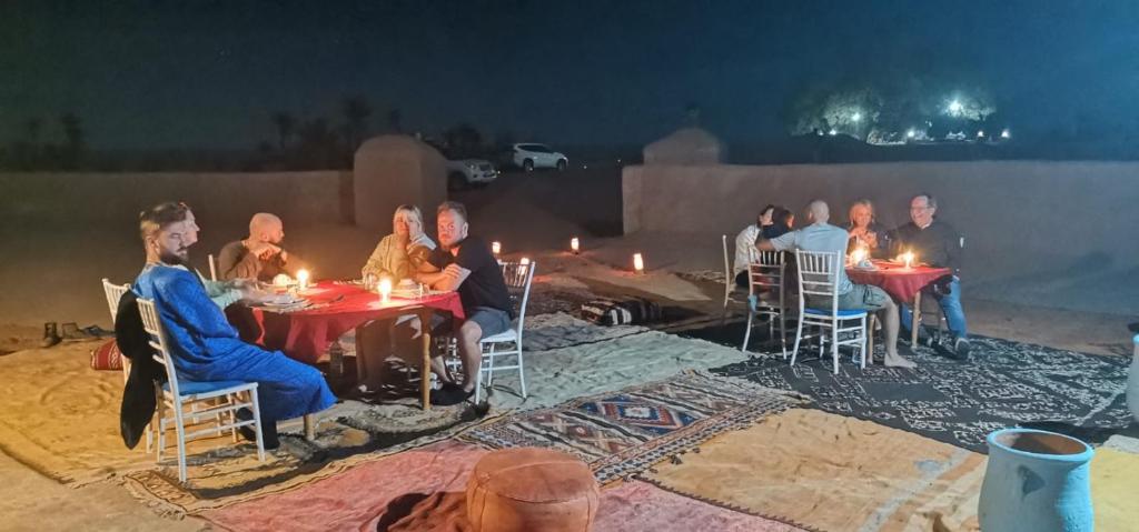 姆哈米德Camp M'hamid Ras N'khal的一群人坐在桌子旁,拿着蜡烛
