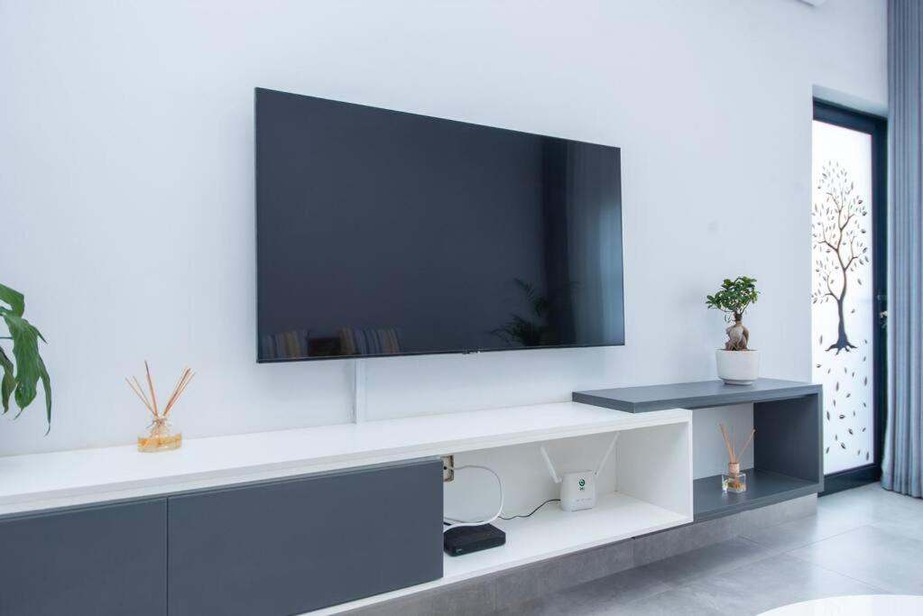 哈博罗内Luxe Lumiere @ The Habitat Alpha的一间客厅,在白色的墙上配有电视