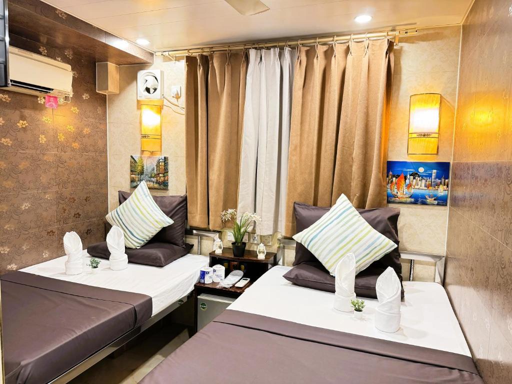 香港New International Guest House的小型客房配有两张床和窗帘