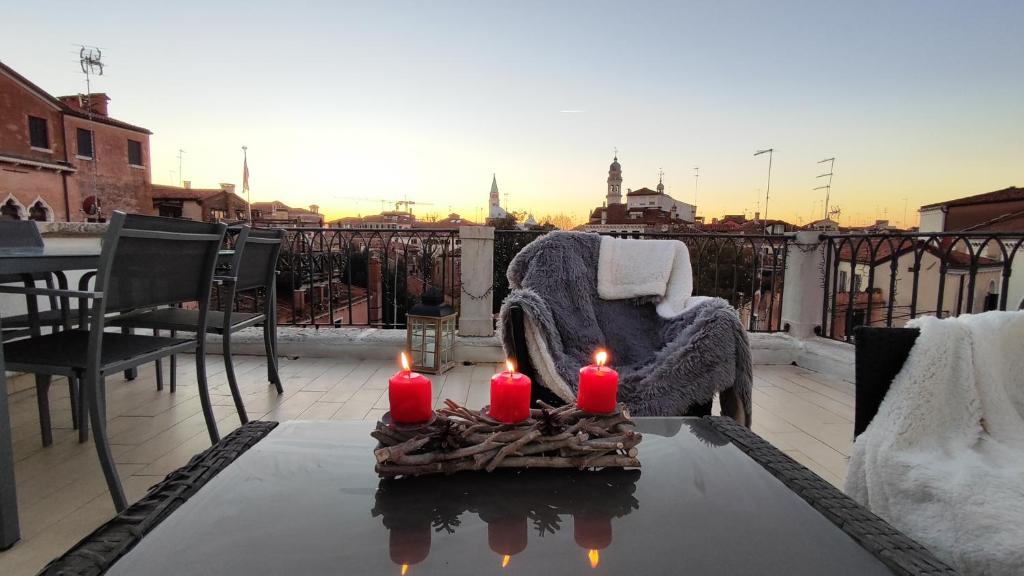 威尼斯VENICE HOLIDAY TERRACE的阳台上的桌子上放着三根蜡烛