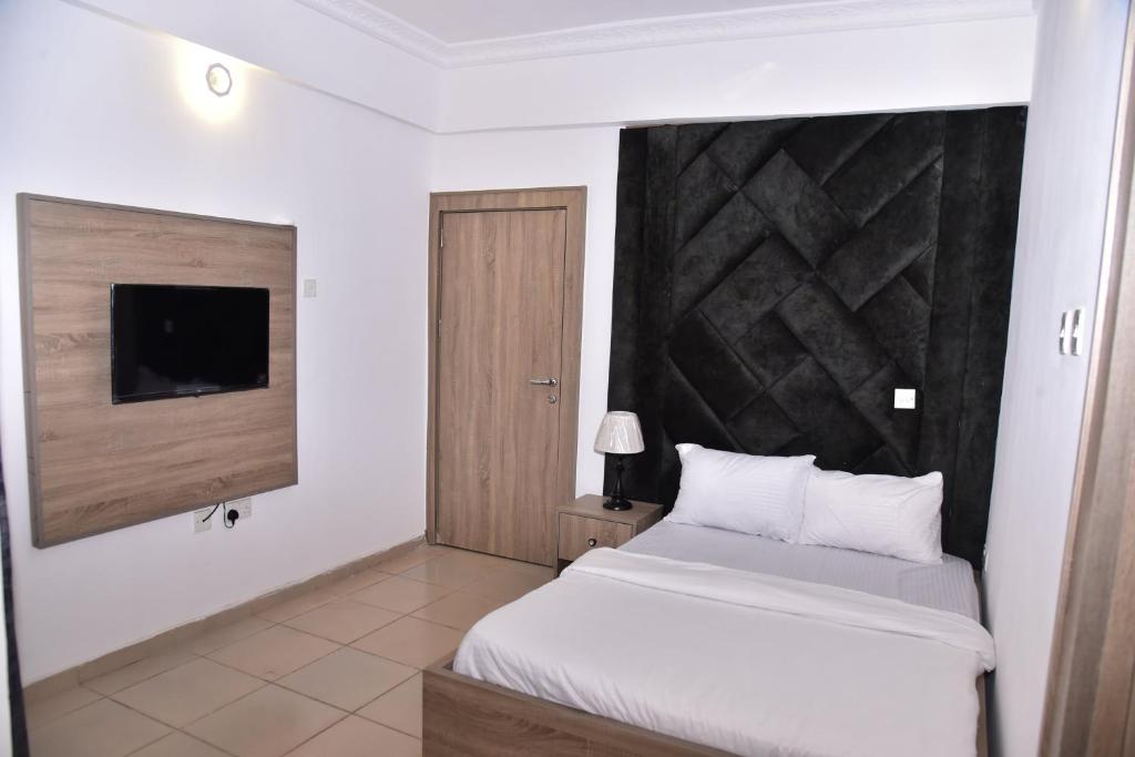 阿布贾1118 Serenity Residence的卧室配有白色的床和电视。