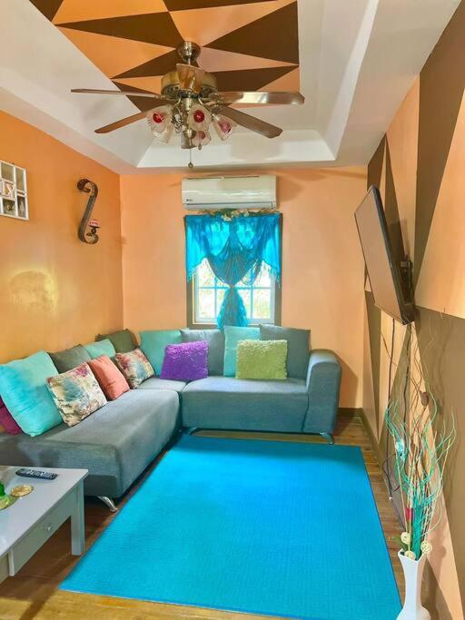 罗阿坦Island style home, low key rental的客厅配有蓝色的沙发和吊扇