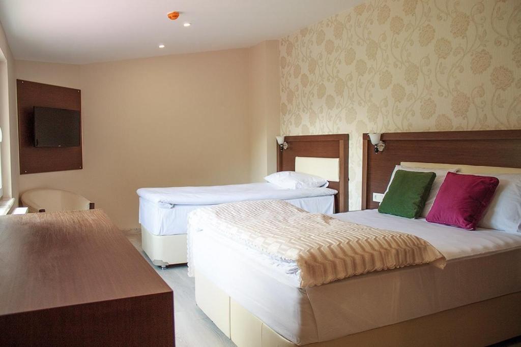 SavsatHotel Green Valley Savsat的酒店客房配有两张带色彩缤纷枕头的床。