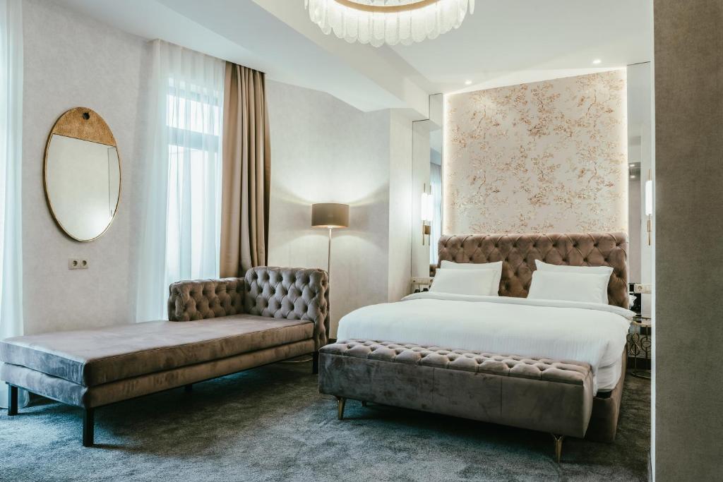 第比利斯Highgarden Hotel的一间卧室配有一张床、一张沙发和一面镜子