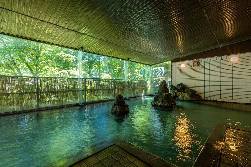 仙北龟之井酒店田泽湖的一间有岩石的房间,里面有一个水池