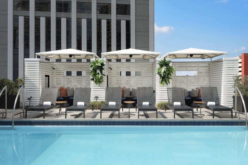 新奥尔良新奥尔良美丽殿酒店的一座带椅子和遮阳伞的游泳池位于一座建筑旁边