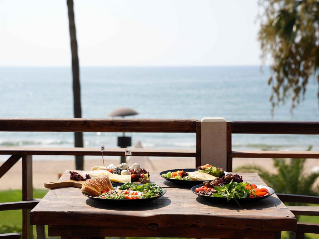 Ar RumaylahLaguava Resort的一张木桌,上面有三盘食物