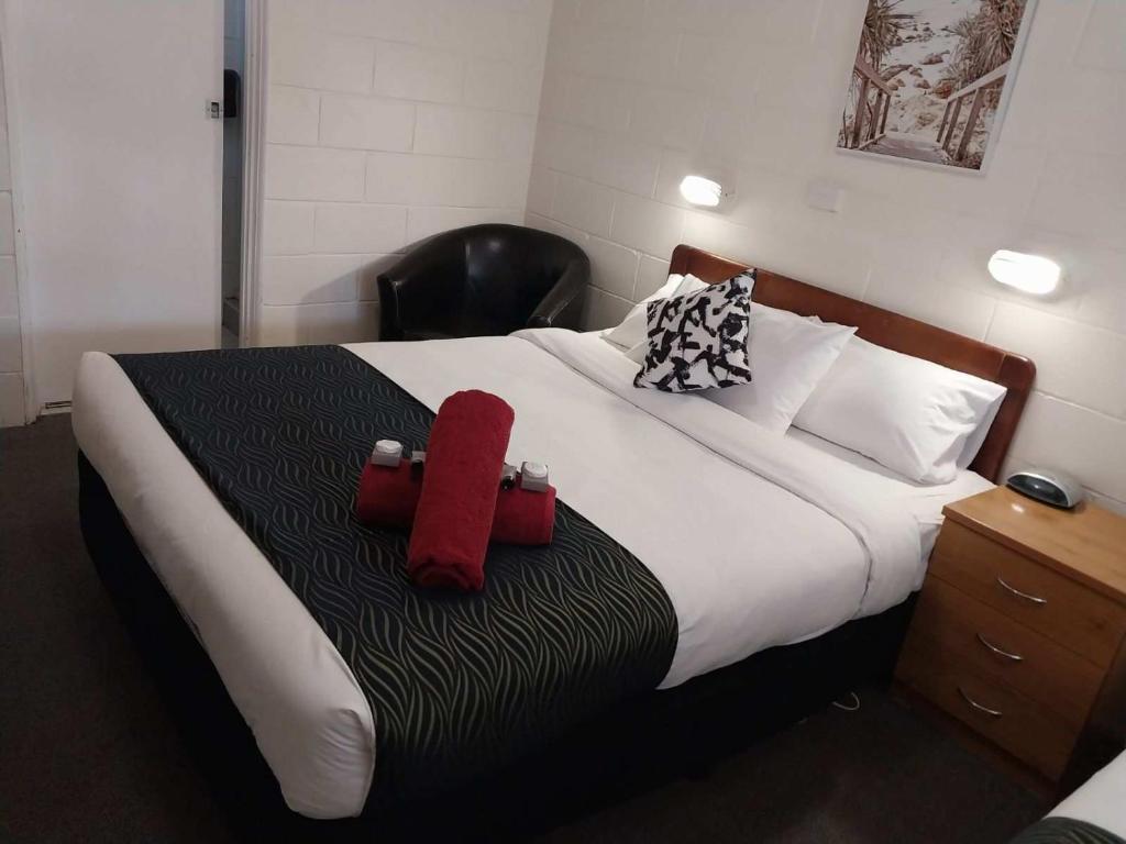 Peak HillGolden Peak Motel PeakHill的一间卧室配有一张带两个红色枕头的床