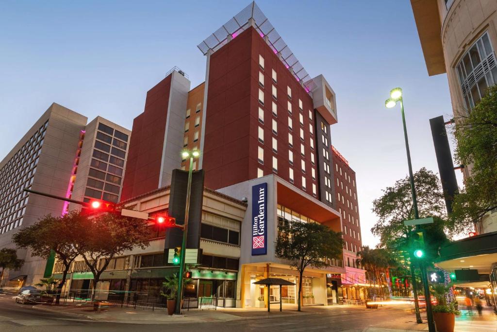 圣安东尼奥Hilton Garden Inn San Antonio Downtown Riverwalk的夜幕降临的城市街道上一座高大的红色建筑
