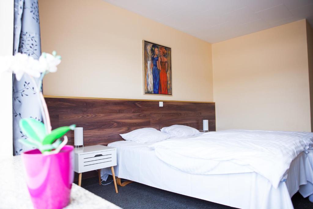 格罗斯滕Gæstehus的卧室配有白色的床和木制床头板