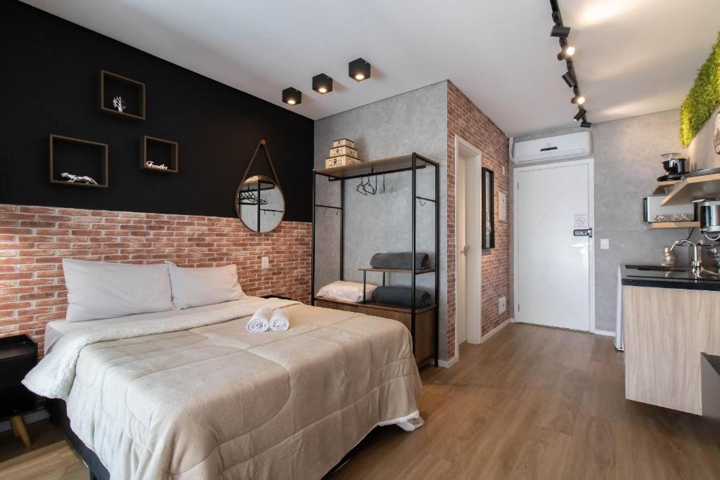 瓜鲁柳斯Apartamento 1106 em condomínio de alto padrão的一间卧室设有一张大床和砖墙