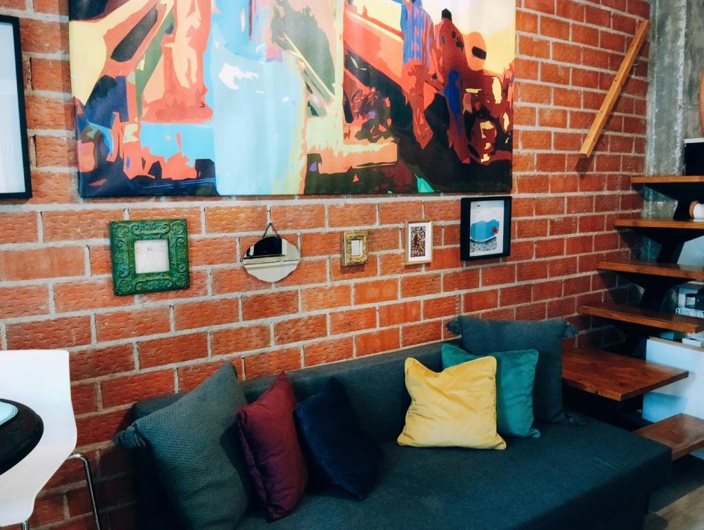 马德里El Pozo-Villalobos Suite的砖墙,带绿色长沙发,有色彩缤纷的枕头
