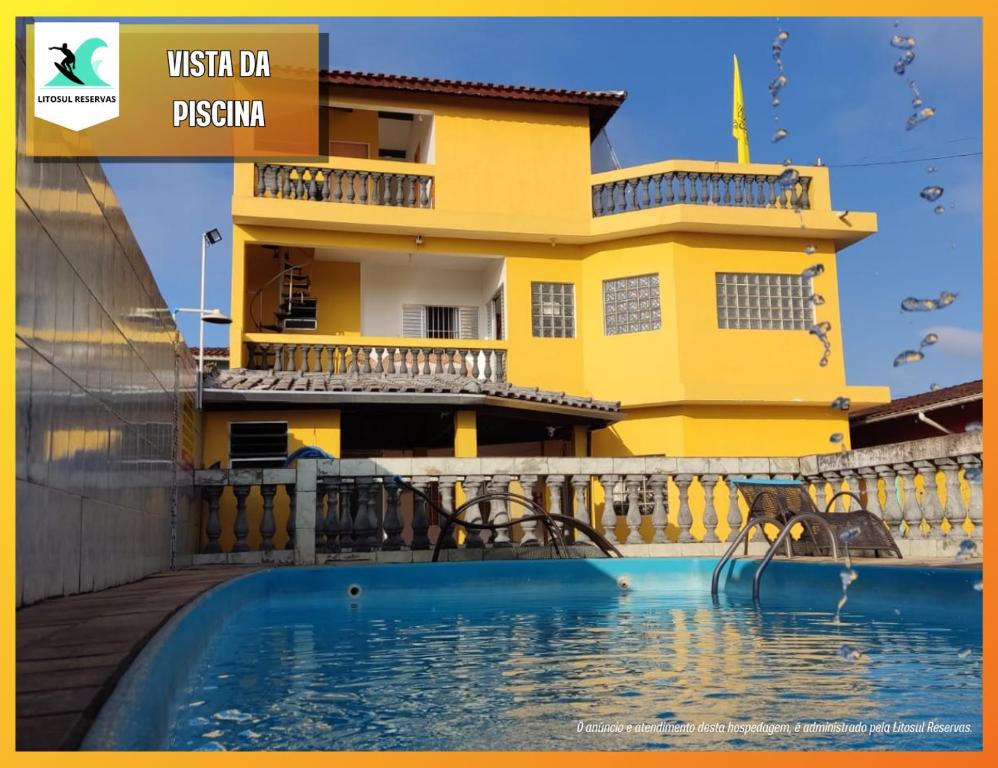 蒙加瓜Hostel Tá Maneiro的黄色的房子,前面有一个游泳池