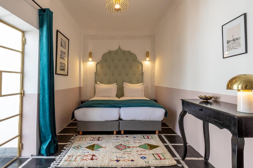 马拉喀什Riad la Parenthèse by Sashema的一间卧室配有一张床和一张桌子,铺有地毯