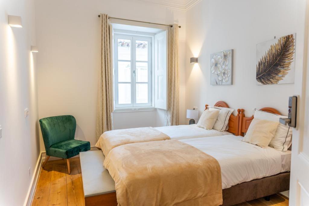 埃武拉Guest House - Palácio Diana的一间卧室配有两张床和一张绿色椅子