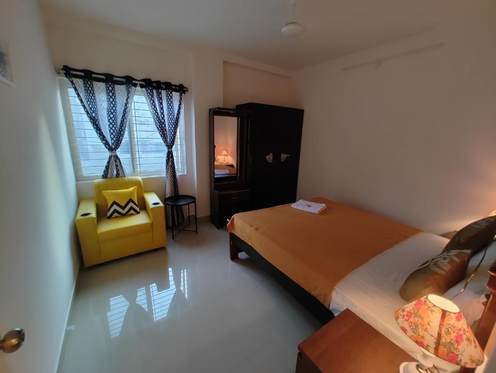 海得拉巴NK Homes - Serviced Apartments的一间卧室配有一张床和一张黄色椅子