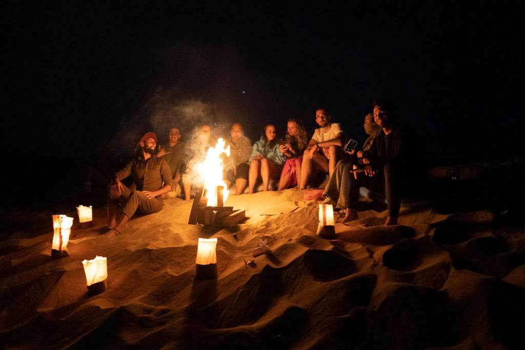 阿加迪尔darna surf house anza的一群人坐在沙子里的火堆旁