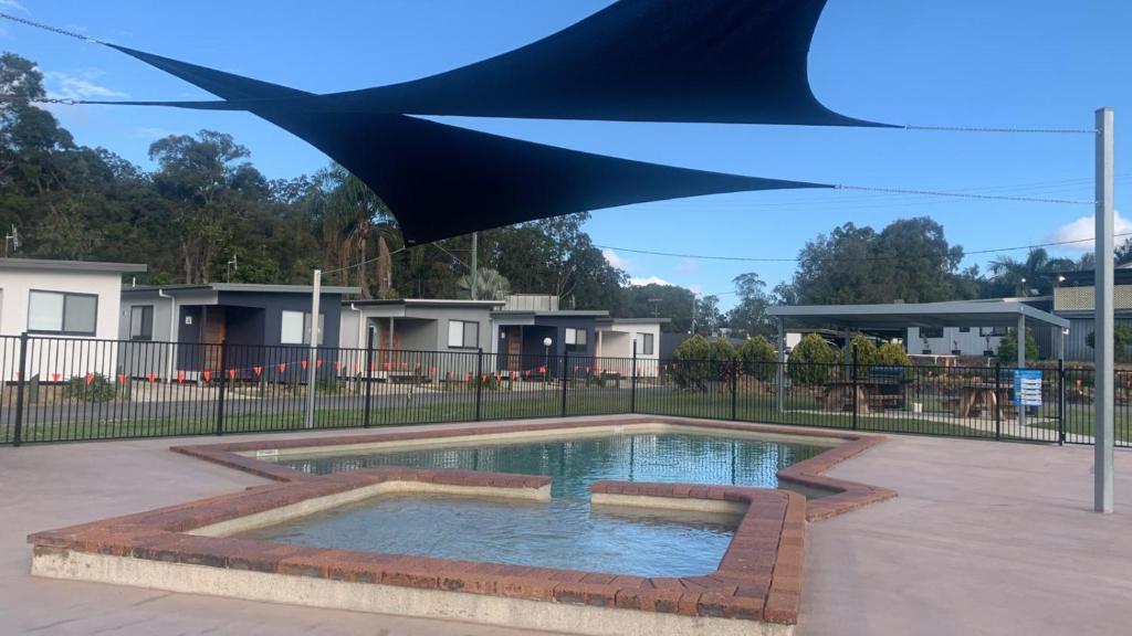 Yandina扬迪纳大篷车公园露营旅馆的游泳池上方设有蓝色遮阳伞