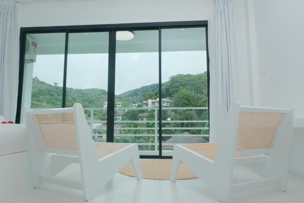 Ka RornMoonE的白色的客房设有两把椅子和大窗户