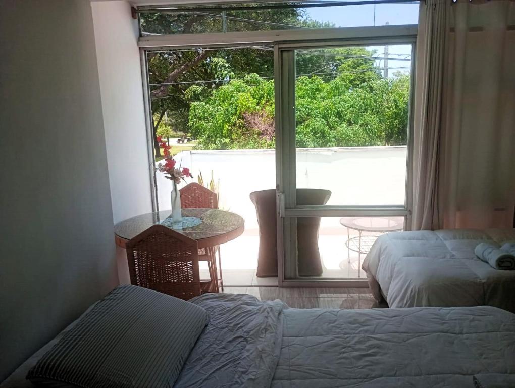 利马Monterrico Suites Hotel的一间卧室配有一张床、一张桌子和一个窗户。