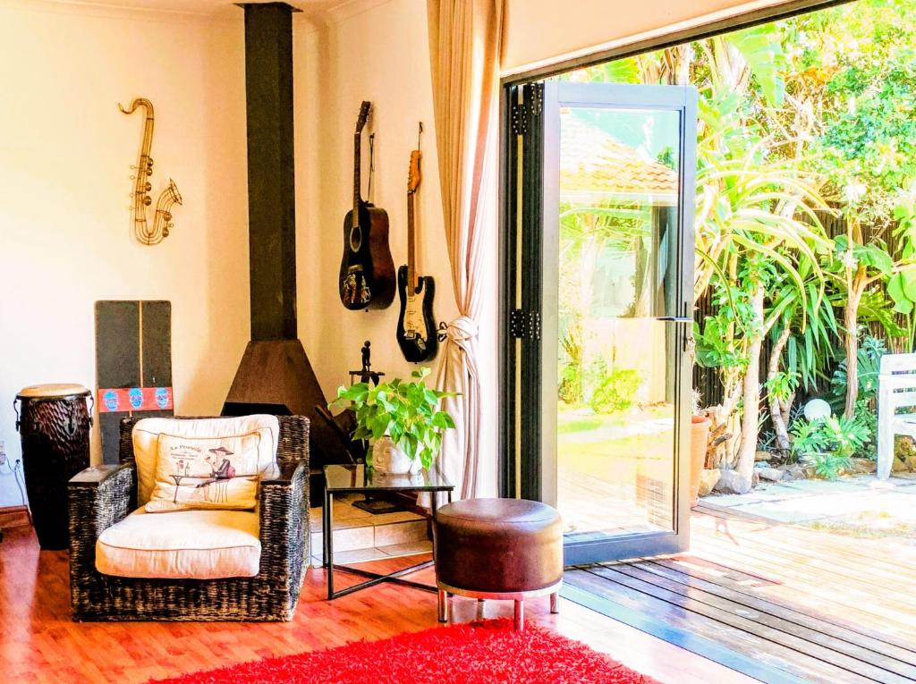 开普敦Spacious home in Cape Towns Blouberg area的客厅配有椅子和吉他,墙上挂着吉他