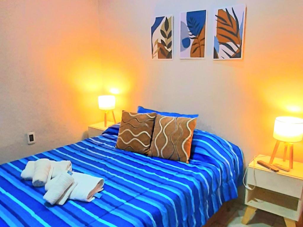 门多萨APART CENTRO RIOJA, Zona Residencial, Parking privado gratis a 100 mts的一间卧室配有一张蓝色的床、枕头和两盏灯。