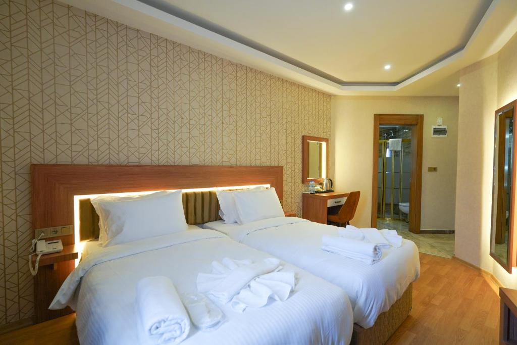 加济安泰普乌古鲁酒店的两张位于酒店客房的床,配有毛巾