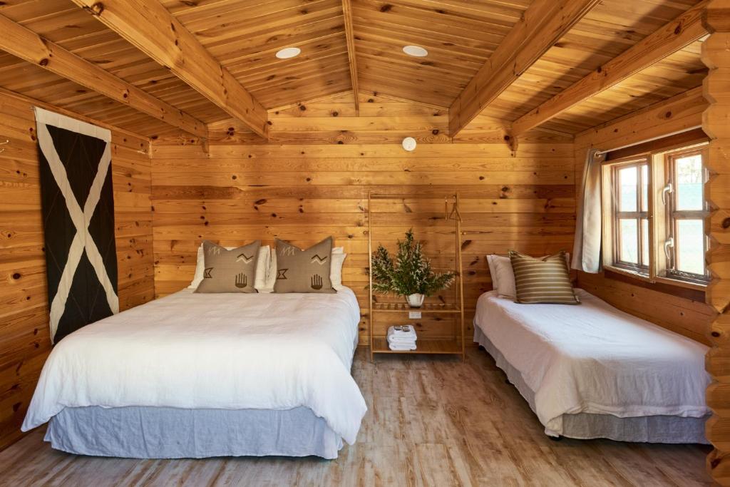 滕特菲尔德Tenterfield Lodge Caravan Park的小木屋卧室设有两张木墙床