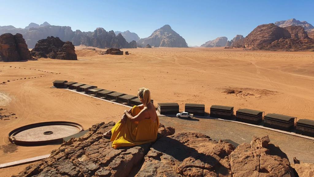 瓦迪拉姆Rum Under The Stars Camp的坐在沙漠岩石上的女人