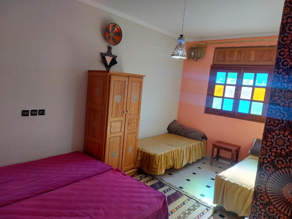 Kasba des Aït MoussaGite Rahhaoui Simo的一间卧室设有两张床、一个橱柜和一个窗口。