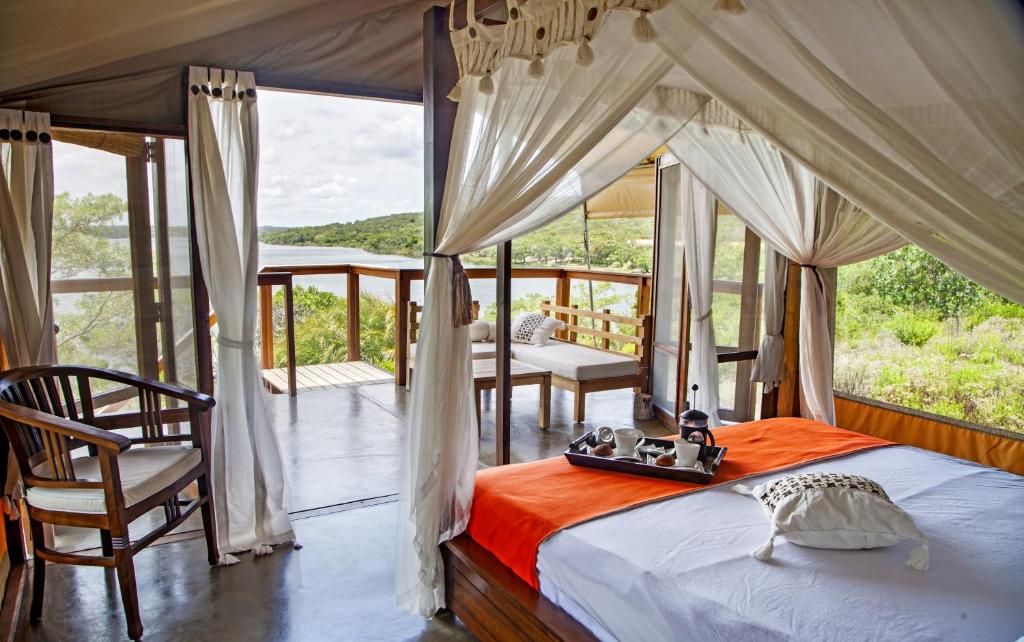 希登盖莱Naara Eco Lodge & Spa的一间卧室设有一张天蓬床和一个阳台