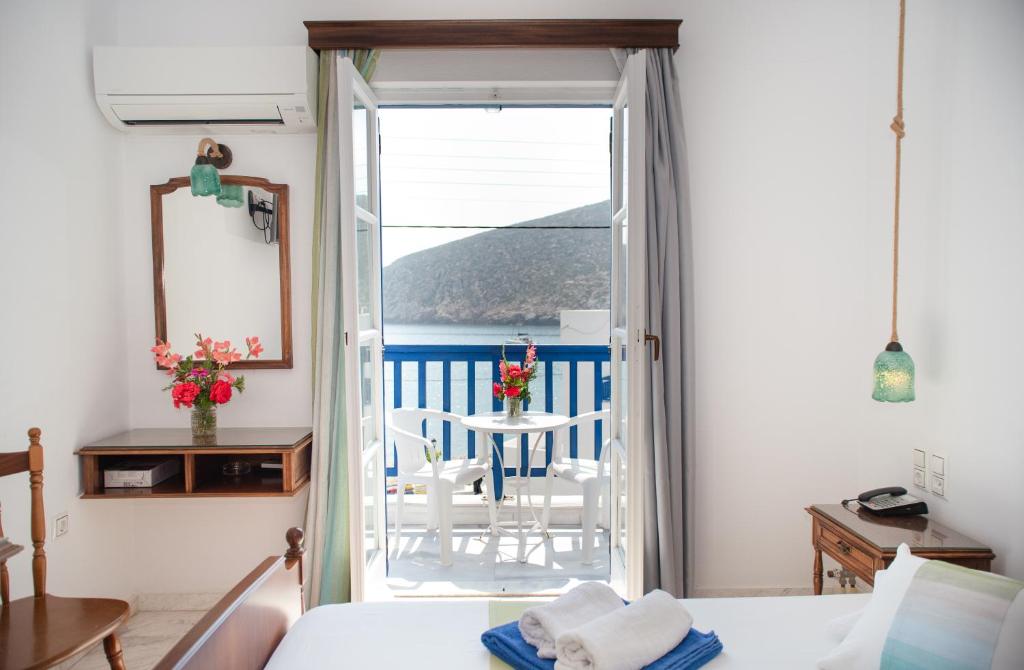 阿波罗Adonis Hotel Naxos的一间卧室设有一扇门,可通往带桌子的阳台