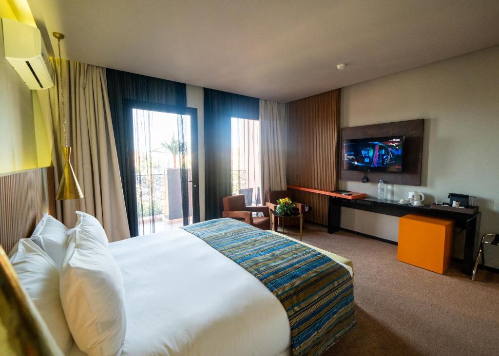 马拉喀什Hotel Le Rocher Marrakech的酒店客房设有一张大床和一台电视。