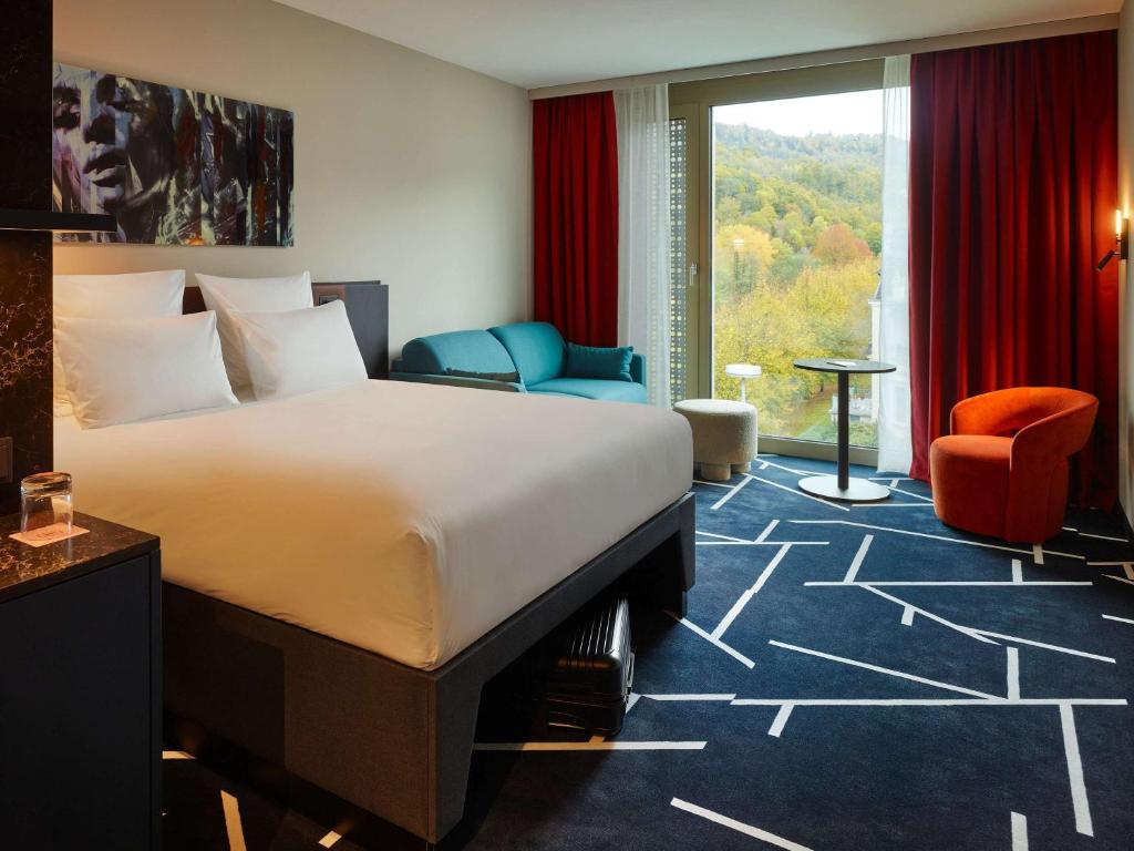 巴登-巴登TRIBE Baden-Baden的酒店客房带床、椅子和窗户