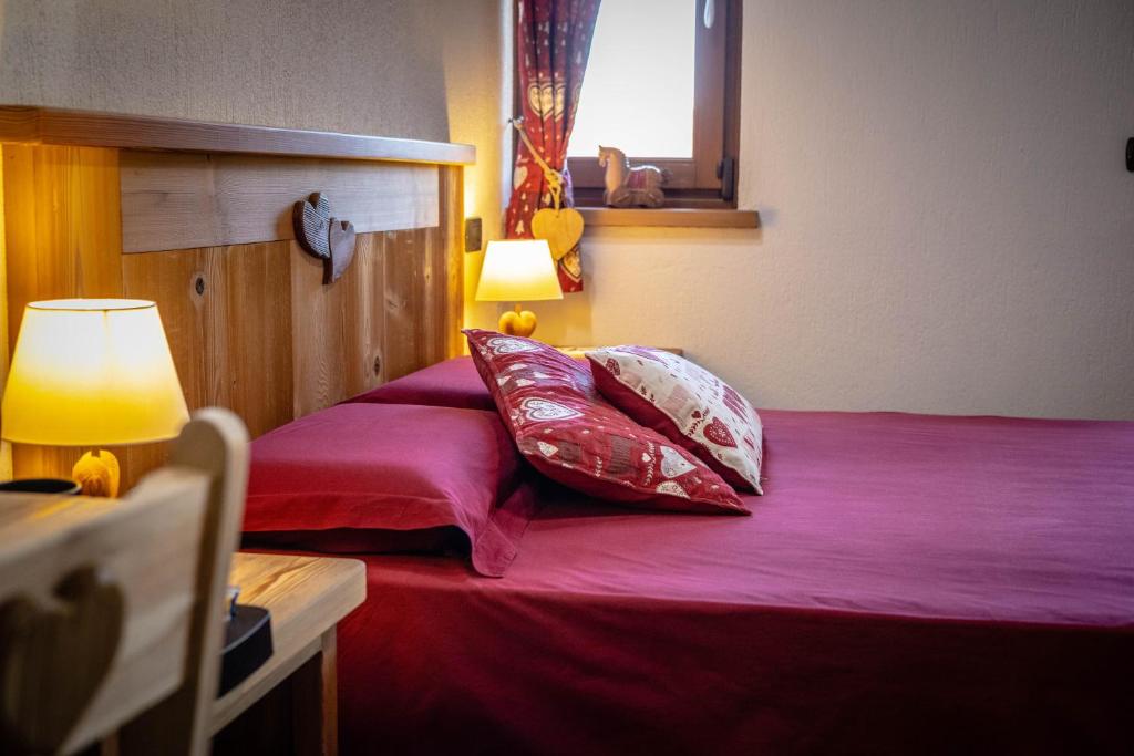 布吕松Le Coin des Mélèzes - NATURE & TREK的一间卧室配有一张带红色床单和枕头的床。