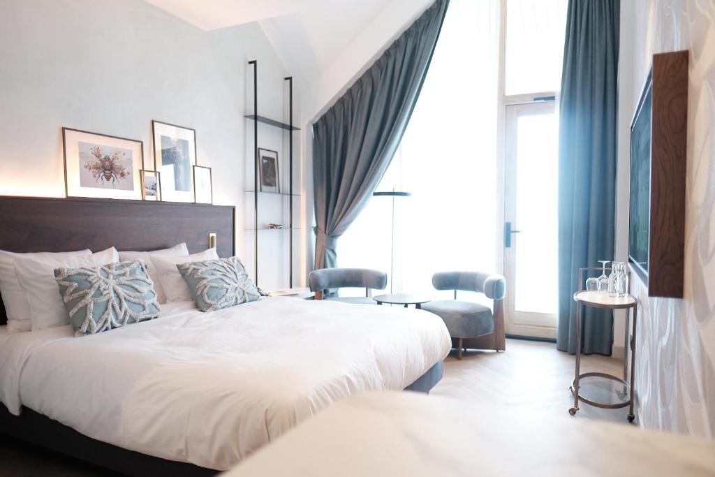奥弗芬Boutique Hotel Blendin Bloemendaal aan Zee的一间卧室配有一张带蓝色窗帘的大床