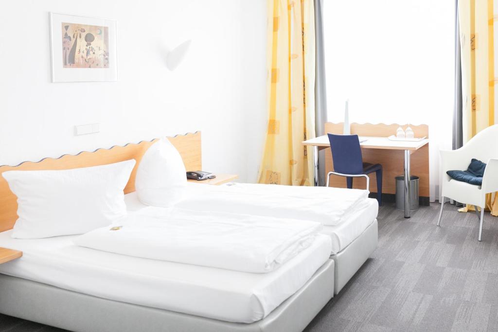 明斯特安姆毕恩特酒店的一张白色的床,位于带桌椅的房间