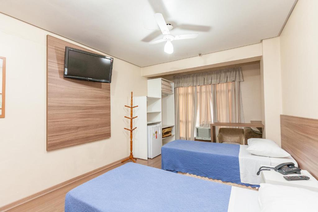 阿雷格里港Letto Hotel Porto Alegre的一间卧室配有两张床和一台平面电视