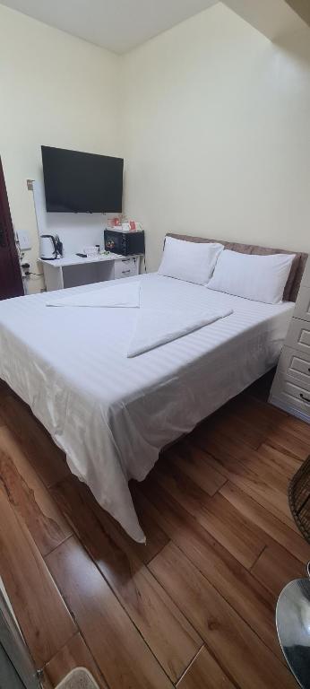 内罗毕JVcribstudios-Ndemi gardens apartments的一张铺有木地板的带白色床单的大床