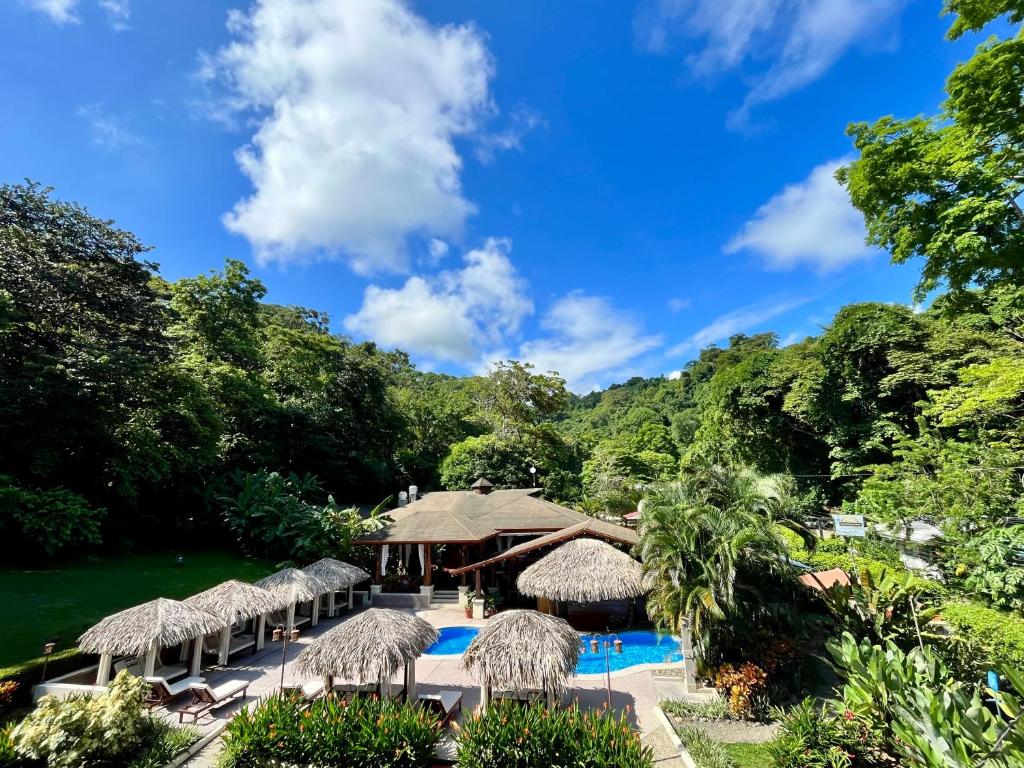 曼努埃尔安东尼奥Hotel Playa Espadilla & Gardens的一个带游泳池和稻草遮阳伞的度假村