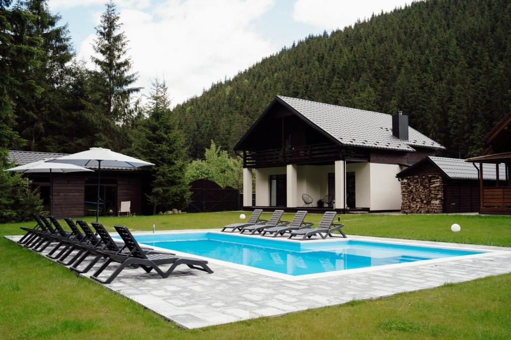布克维Berghaus Bukovel的一个带躺椅的游泳池以及一座房子