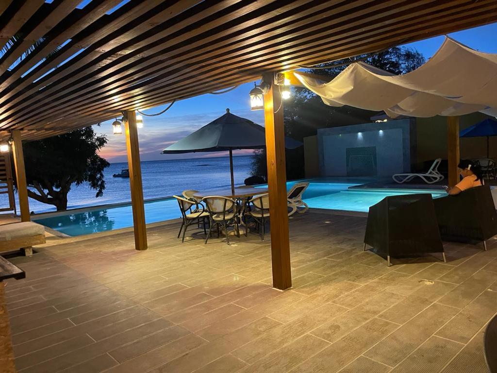 蓬塔露奇亚Hotel Sand Bay的一个带桌子和遮阳伞的庭院和一个游泳池