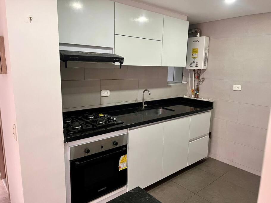 波哥大Apartamento Barrio La Felicidad的厨房配有白色橱柜和炉灶烤箱。