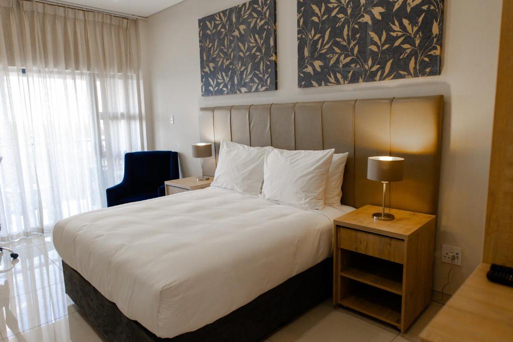 克莱克斯多普Acres Inn Klerksdorp的卧室配有一张白色大床和一把椅子