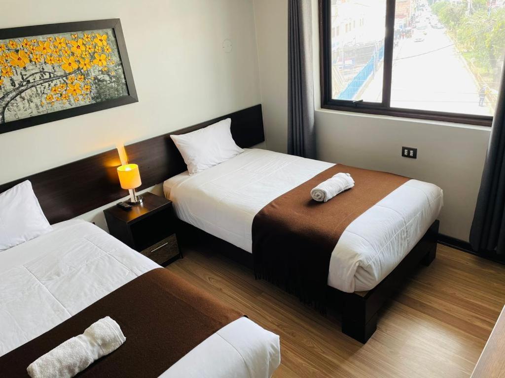 库斯科Tikala Cusco Boutique Hotel的酒店客房设有两张床和窗户。
