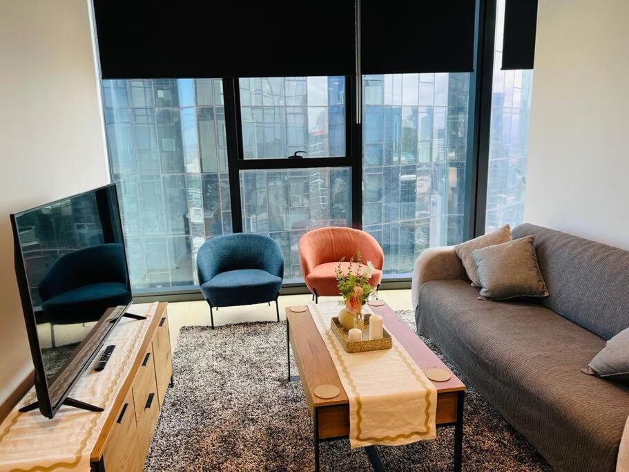 墨尔本2 BR Apartment Melbourne Square的客厅配有沙发和两把椅子
