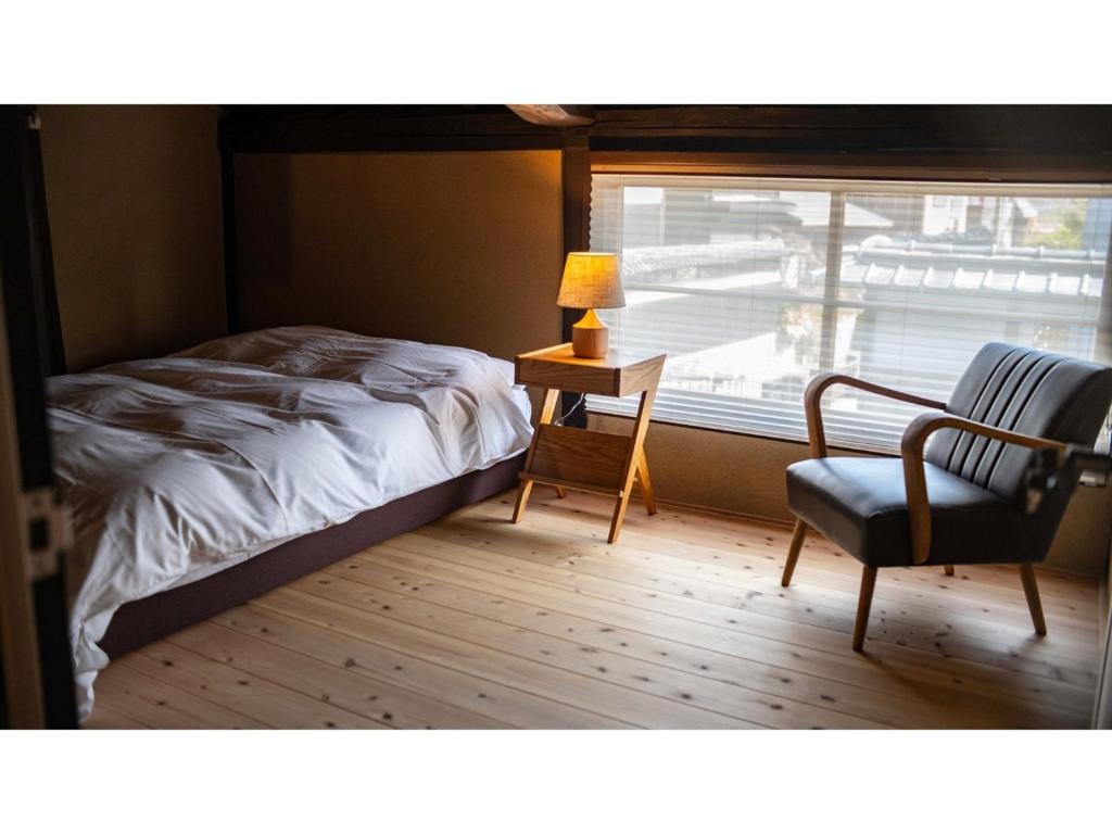 TatsunoKominka Hotel kurasu - Vacation STAY 24260v的卧室配有床、椅子和窗户。